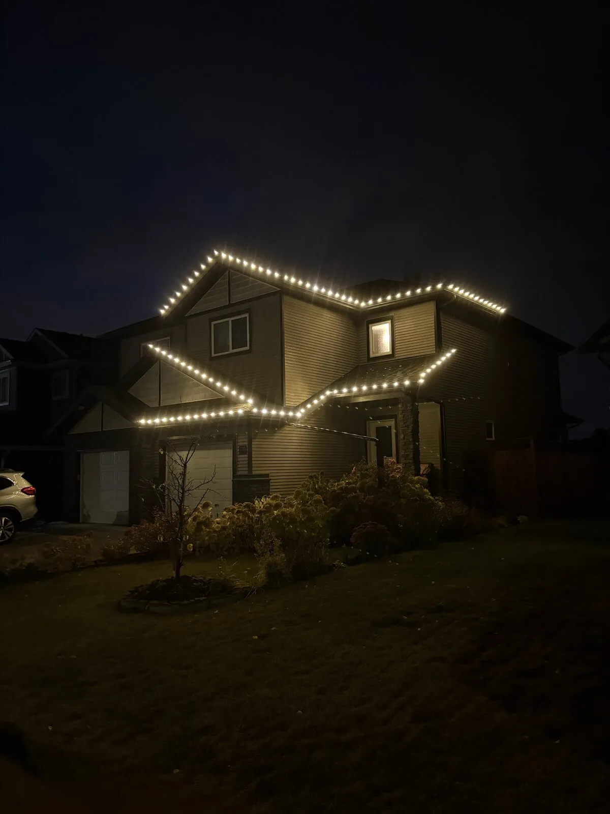 Home with warm white C9 lights outlining layered rooflines and peaks at night